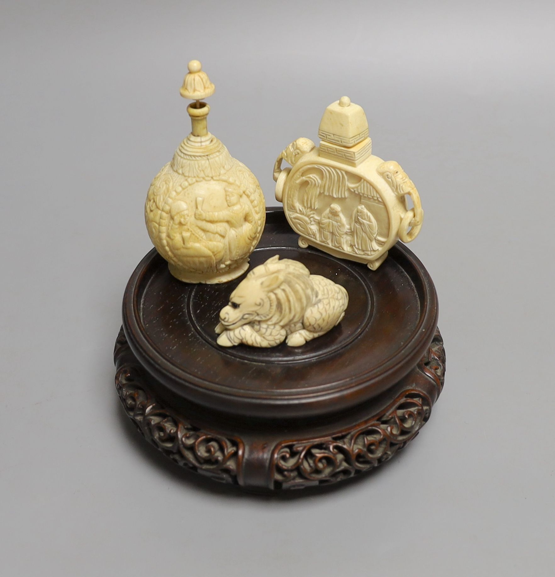 A 19th-century European carved ivory snuff bottle, and an early 20th century Chinese ivory snuff bottle and an ivory Netsuke of a lion-dog and a Chinese hongmu stand (4)